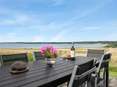 a wooden table with a bottle of wine and flowers at Holiday Home Ephra - 250m to the fjord by Interhome in Roslev