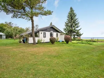 a small white house with a tree in the yard at Holiday Home Kaleva - 200m to the fjord by Interhome in Fur