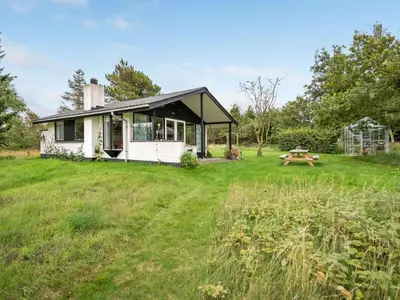 a small white house with a picnic table in a field at Holiday Home Kaleva - 200m to the fjord by Interhome in Fur