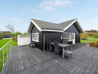 a wooden deck with a table and chairs on it at Holiday Home Clarita - 300m to the fjord by Interhome in Roslev