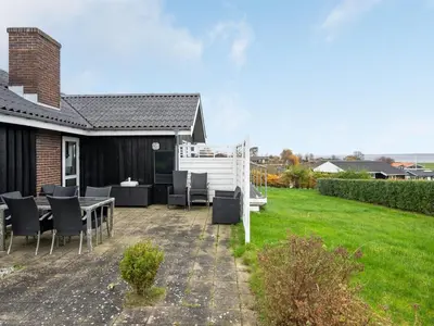 a patio with a table and chairs in a yard at Holiday Home Clarita - 300m to the fjord by Interhome in Roslev