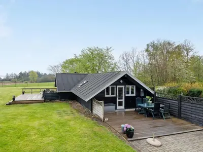 a black shed with a deck and a patio at Holiday Home Henrieke - 250m to the fjord by Interhome in Roslev