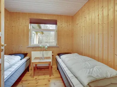 two beds in a room with a table and a window at Holiday Home Tille - 700m to the fjord by Interhome in Roslev