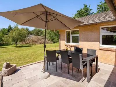 a table and chairs with an umbrella on a patio at Holiday Home Tille - 700m to the fjord by Interhome in Roslev