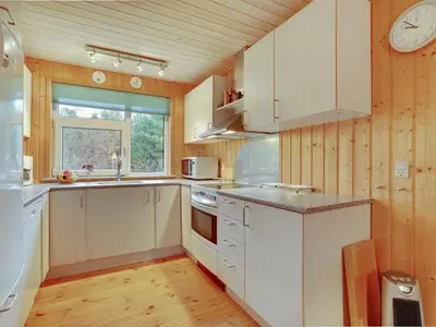 a kitchen with white cabinets and a clock on the wall at Holiday Home Tille - 700m to the fjord by Interhome in Roslev