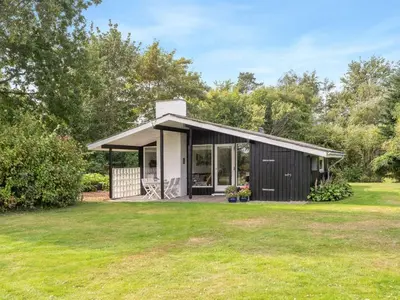 a small black cottage with a grass yard at Holiday Home Suoma - 400m to the fjord by Interhome in Roslev