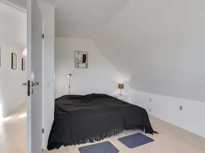 a bedroom with a black bed in a white room at Holiday Home Auguste - 1-5km to the fjord by Interhome in Fur