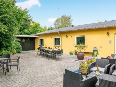 a patio with tables and chairs and a yellow house at Holiday Home Rina - 30m to the fjord by Interhome in Fur