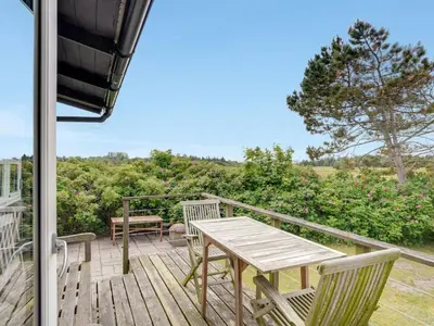 a wooden deck with a table and chairs on it at Holiday Home Gren - 90m to the fjord by Interhome in Roslev