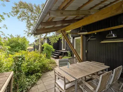 an outdoor patio with a wooden table and chairs at Holiday Home Gren - 90m to the fjord by Interhome in Roslev
