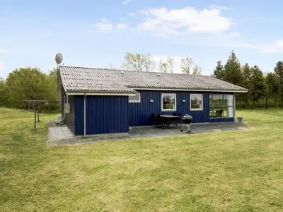 a blue house with a grill in a field at Holiday Home Mikkeline - 400m to the fjord by Interhome in Øster Assels