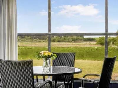 a table and chairs with a vase of flowers on it at Holiday Home Mikkeline - 400m to the fjord by Interhome in Øster Assels