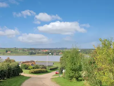 a dirt road next to a lake with a house at Holiday Home Imgert - 300m to the fjord by Interhome in Løgstrup
