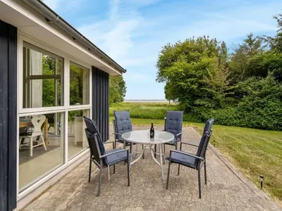 a patio with a table and chairs and a view of a field at Holiday Home Ødger - 150m to the fjord by Interhome in Åbybro