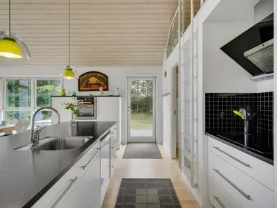 a kitchen with white cabinets and black counter tops at Holiday Home Ødger - 150m to the fjord by Interhome in Åbybro