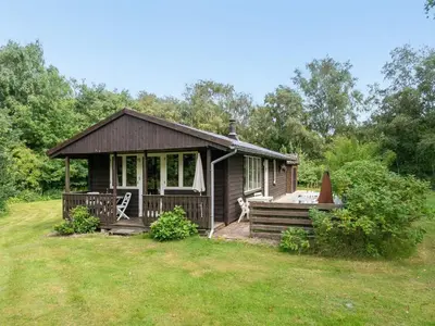 a small cabin with a porch and a yard at Holiday Home Lennert - 100m to the fjord by Interhome in Åbybro