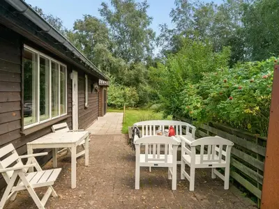 a patio with white tables and chairs next to a house at Holiday Home Lennert - 100m to the fjord by Interhome in Åbybro