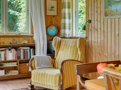 a living room with a chair and a book shelf at Holiday Home Lennert - 100m to the fjord by Interhome in Åbybro