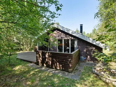 a small house with a deck in the woods at Holiday Home Jussi - 3-5km from the sea by Interhome in Brovst