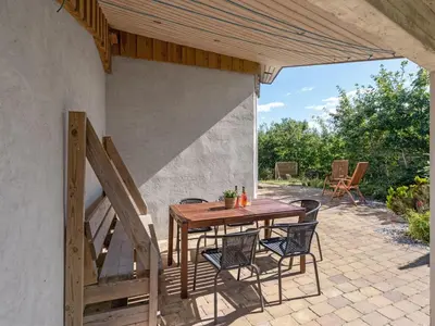 a wooden table and chairs on a patio at Holiday Home Ullvi - 3-8km from the sea by Interhome in Brovst