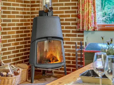 a fireplace in a living room next to a table at Holiday Home Carina - 5km from the sea by Interhome in Brovst
