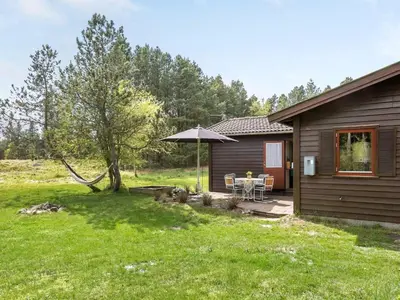 a house with a table and an umbrella in a yard at Holiday Home Carina - 5km from the sea by Interhome in Brovst