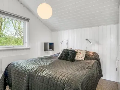 a bedroom with a bed with two lamps and a window at Holiday Home Eske - 200m to the fjord by Interhome in Åbybro