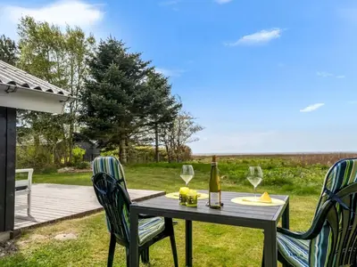 a table with two chairs and a bottle of wine at Holiday Home Eske - 200m to the fjord by Interhome in Åbybro