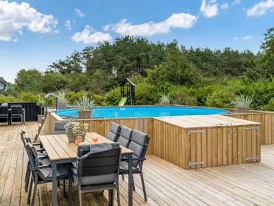 a deck with a table and chairs next to a swimming pool at Holiday Home Asel - 4km from the sea by Interhome in Brovst