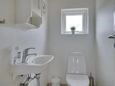 a bathroom with a sink and a toilet and a window at Holiday Home Asel - 4km from the sea by Interhome in Brovst