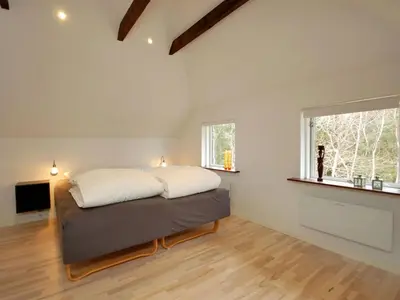 a bedroom with a large bed in a room with two windows at Holiday Home Rigitte - 1-5km from the sea by Interhome in Pandrup