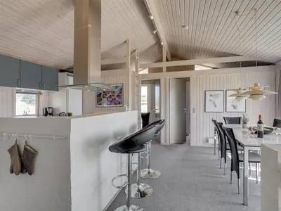a kitchen and dining room with a bar with black chairs at Holiday Home Fanney - 100m from the sea by Interhome in Pandrup
