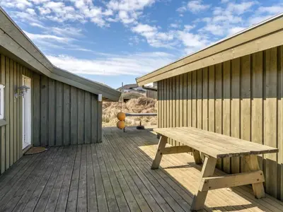 a wooden bench sitting on a deck next to a building at Holiday Home Fanney - 100m from the sea by Interhome in Pandrup
