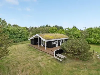 a small house with a deck in a field at Holiday Home Evan - 1-3km from the sea by Interhome in Pandrup
