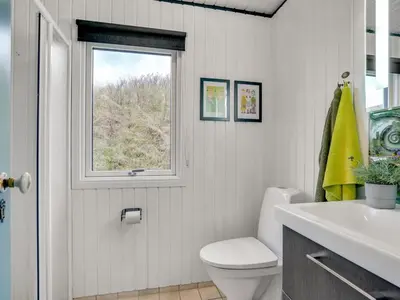 a bathroom with a white toilet and a window at Holiday Home Emiline - 250m from the sea by Interhome in Saltum