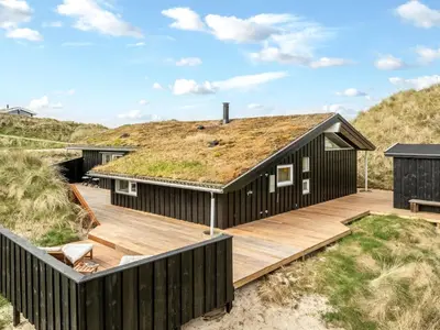 a black house with a grass roof at Holiday Home Nielsigne - 400m from the sea by Interhome in Blokhus