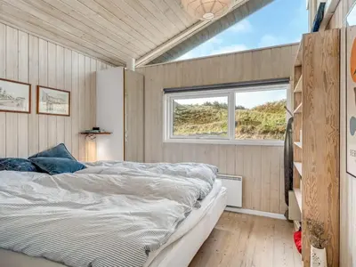 a bedroom with a bed and a window at Holiday Home Nielsigne - 400m from the sea by Interhome in Blokhus