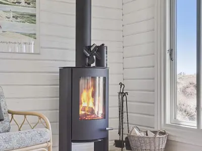 a wood stove in a living room with a fireplace at Holiday Home Baltur - 650m from the sea by Interhome in Saltum