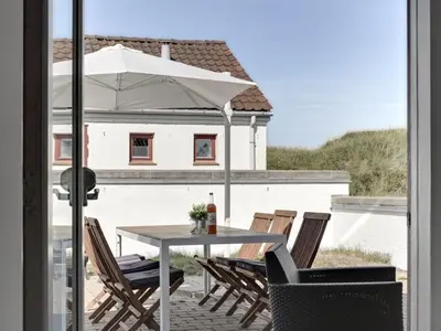 a table and chairs with an umbrella on a patio at Holiday Home Marjon - 400m from the sea by Interhome in Pandrup