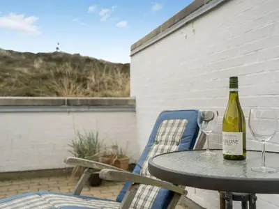 a bottle of wine sitting on a table with two glasses at Holiday Home Emiljan - 400m from the sea by Interhome in Pandrup