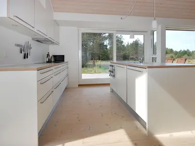 a kitchen with white cabinets and a large window at Holiday Home Melinda - 2km from the sea by Interhome in Pandrup