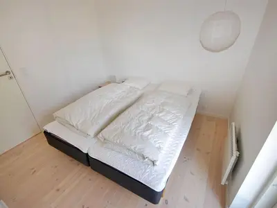 a white bed in a room with a wooden floor at Holiday Home Melinda - 2km from the sea by Interhome in Pandrup