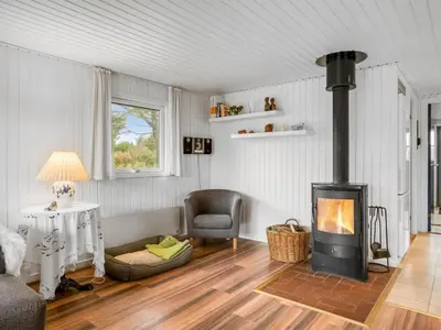 a living room with a fireplace and a chair at Holiday Home Birghir - 1-5km from the sea by Interhome in Blokhus