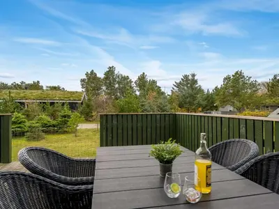 a bottle of wine sitting on a table on a patio at Holiday Home Birghir - 1-5km from the sea by Interhome in Blokhus