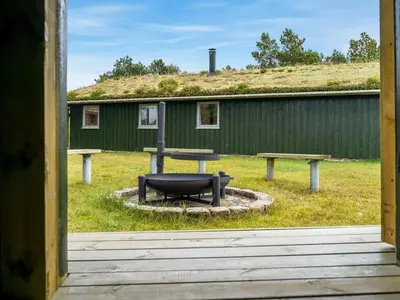 a table and benches in front of a green building at Holiday Home Birghir - 1-5km from the sea by Interhome in Blokhus