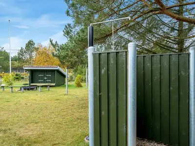 a green fence in a yard with a picnic table at Holiday Home Birghir - 1-5km from the sea by Interhome in Blokhus