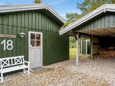 a green building with a white door and a bench at Holiday Home Birghir - 1-5km from the sea by Interhome in Blokhus