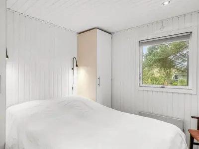 a white bedroom with a bed and a window at Holiday Home Birghir - 1-5km from the sea by Interhome in Blokhus