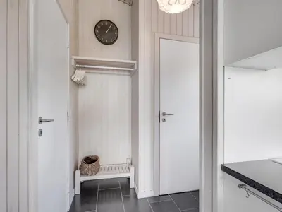 a hallway with a clock on the wall and a door at Holiday Home Driss - 500m from the sea by Interhome in Pandrup
