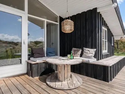 a wooden porch with a table and a window at Holiday Home Driss - 500m from the sea by Interhome in Pandrup